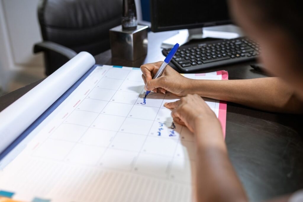 Time-Blocking Isn't About Your Calendar — It's About Your Attention Person writing and planning on a desk calendar