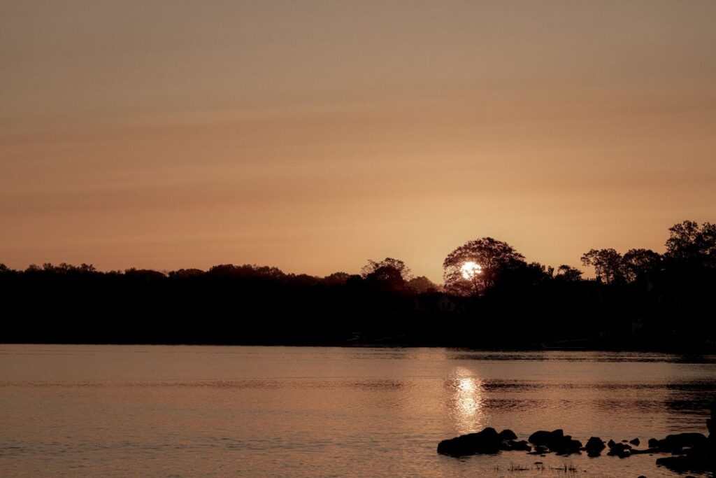 How to Recover From a Bad Day Without Losing the Week Calm lake at sunset with silhouetted trees and warm golden reflections